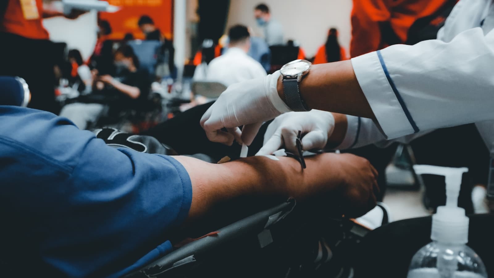 A clinician in gloves attending to a patient's arm.
