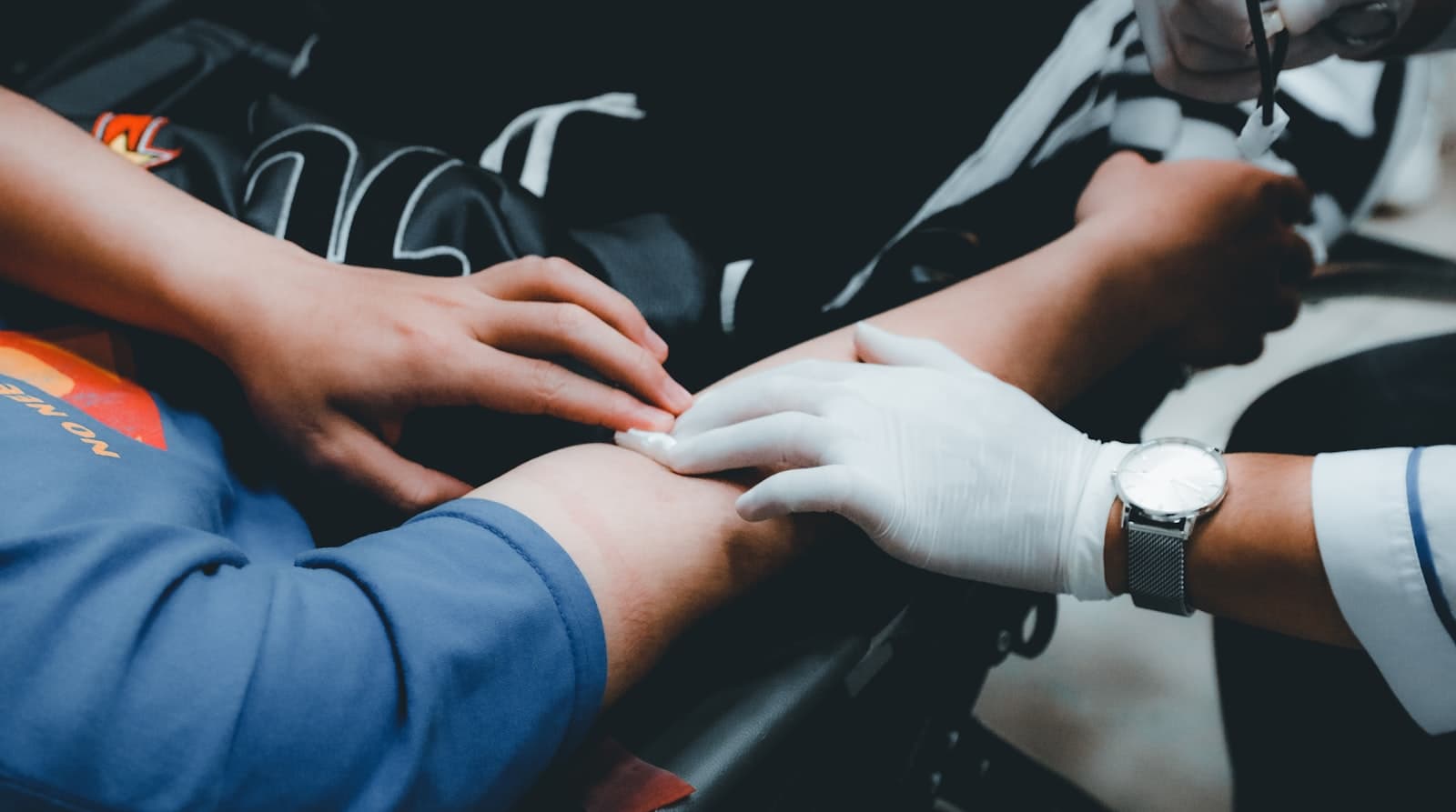 A gloved clinician checking a patient's arm during treatment.